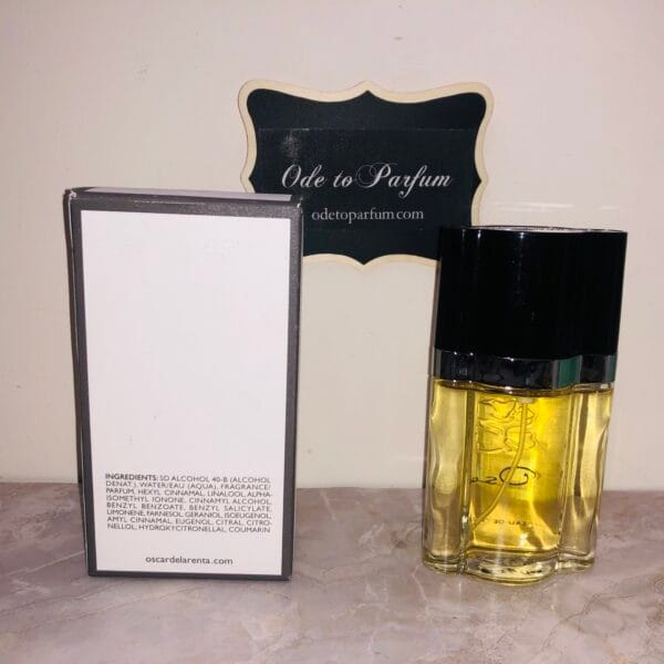 backs of Oscar by Oscar de la Renta perfume, next to box, in front of Ode to Parfum sign,